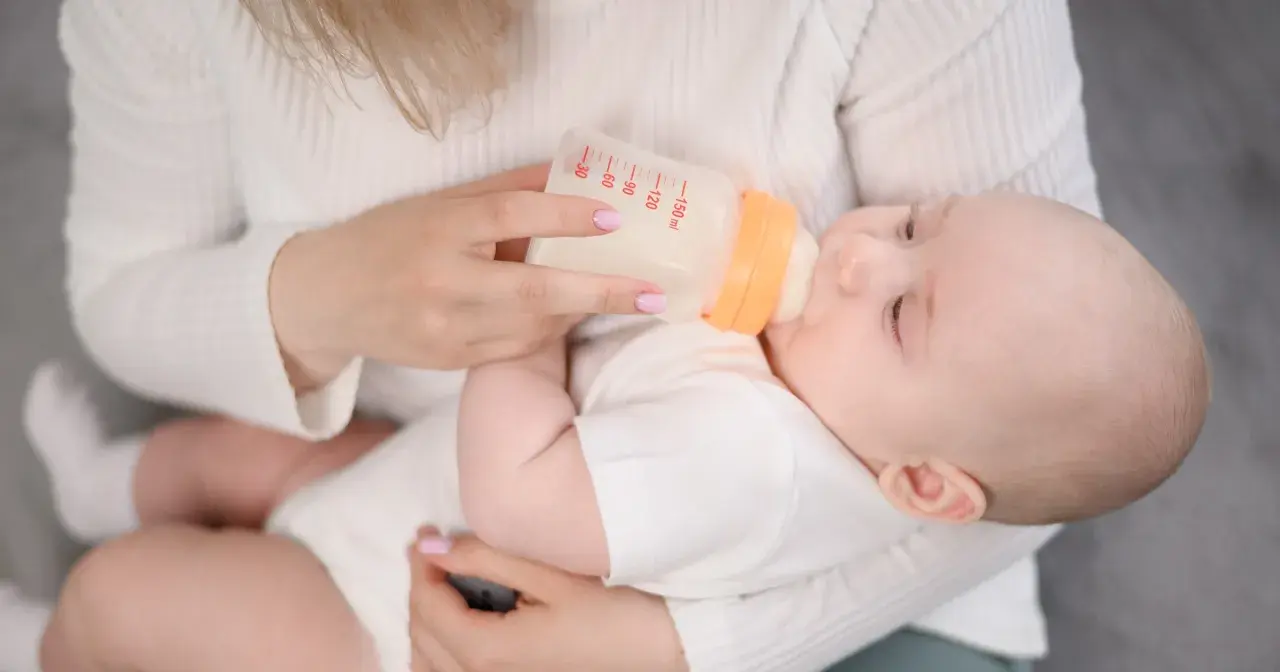 Mama karmi dziecko butelką. Choć mleko Bebilon wycofane, maluch spokojnie pije.