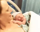 Noworodek śpi na piersi mamy, przygotowując się do karmienia. To piękny początek laktacji i więzi.