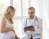 Lekarz wyjaśnia ciężarnej pacjentce, co to jest GBS, pokazując coś na tablecie.
