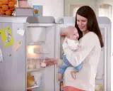 Mama z dzieckiem przy lodówce, gdzie przechowywanie mleka matki jest łatwe dzięki specjalnym pojemnikom.