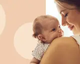 Ciepły uścisk mamy po narodzinach dziecka. Maluch wtulony w ramię, patrzący z zaciekawieniem.