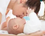 Czuły pocałunek mamy dla jej 3 miesięcznego dziecka.