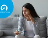 Zmartwiona kobieta trzyma test ciążowy. Ikona progesteronu sugeruje niski progesteron objawy.
