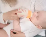 Mama karmi dziecko butelką. Choć mleko Bebilon wycofane, maluch spokojnie pije.