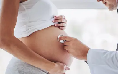 Lekarz osłuchuje brzuch ciężarnej kobiety, która jest w 24 tygodniu ciąży.