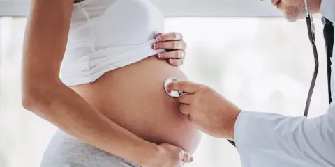 Lekarz osłuchuje brzuch ciężarnej kobiety, która jest w 24 tygodniu ciąży.