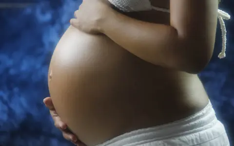 Brzuch kobiety w ciąży, delikatnie dotykany dłońmi. Warto skonsultować z lekarzem stosowanie leków, np. ibuprom w ciąży.