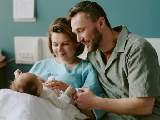 Szczęśliwi rodzice z noworodkiem w szpitalu. Dowiadują się o świadczenia po urodzeniu dziecka.