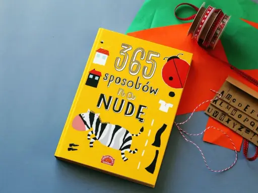 Żółta książka "365 sposobów na nudę" z zebrą, biedronką i literami.