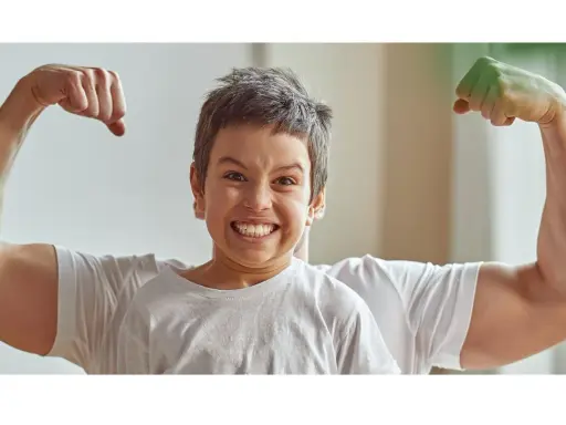 Chłopiec z miną jak po **buncie 5 latka** pokazuje swoje małe bicepsy, podczas gdy za nim widać potężne ramiona taty.