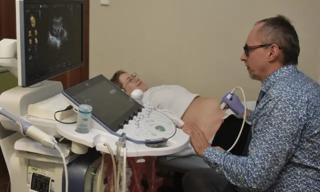 Lekarz wykonuje usg 3 trymestru. Na ekranie widać obraz dziecka, a pacjentka leży spokojnie.