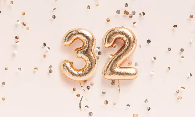 Złote balony z cyframi 3 i 2, otoczone konfetti. To już 32 tydzień ciąży, czas na świętowanie!